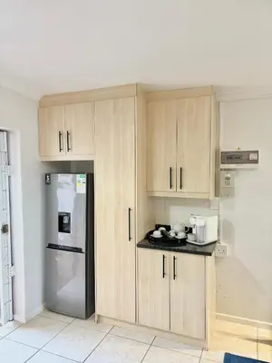 a kitchen with wooden cabinets and a refrigerator at Cottage in Cape Town