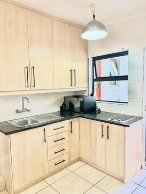 a kitchen with wooden cabinets and a sink and a window at Cottage in Cape Town