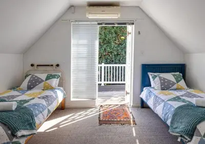 a attic room with two beds and an open door at Beachcomber's Rest in Hermanus