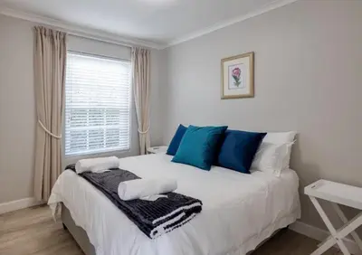 a bedroom with a large white bed with blue pillows at Beachcomber's Rest in Hermanus