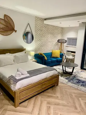 a bedroom with a large bed and a blue couch at On Park Century City Cozy Apartment in Cape Town