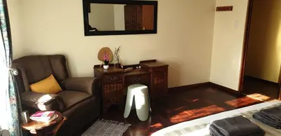 a living room with a couch and a chair and a mirror at Protea-Sabr in Sir Lowry Pass