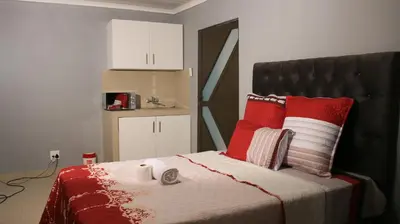 a bedroom with a bed with red and white pillows at Gift Guest house 3 in Cravenby