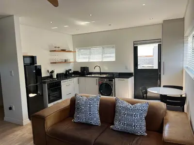 a living room with a couch and a kitchen at Apartment Paradys - Serviced in Stellenbosch