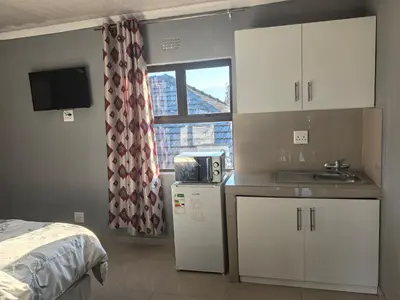 a small kitchen with white cabinets and a window at Gift guest house 4 in Cravenby