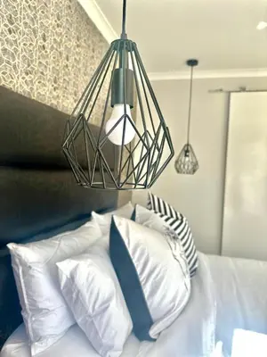a chandelier above a bed with white pillows at Hideaway Haven in Cape Town