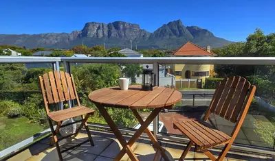 a table and two chairs on a balcony with mountains at Cape Town Studio Apartment in Cape Town