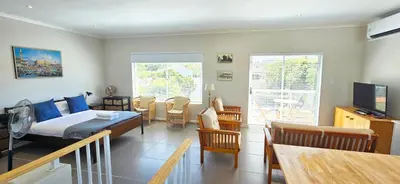 a bedroom with a bed and a dining room with a table at Cape Town Studio Apartment in Cape Town