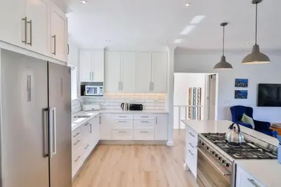 a white kitchen with white cabinets and a refrigerator at Vonkelwyn - enjoy Grotto Beach sunsets in Hermanus