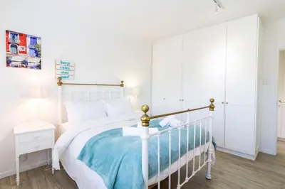 a bedroom with a white bed with a blue blanket at Vonkelwyn - enjoy Grotto Beach sunsets in Hermanus