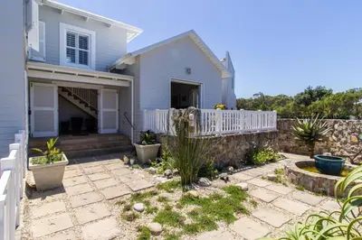 a house with a white fence and a patio at Nautilus on Grotto Beach - heated pool in Hermanus