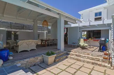 an outdoor deck with a table and chairs at Nautilus on Grotto Beach - heated pool in Hermanus