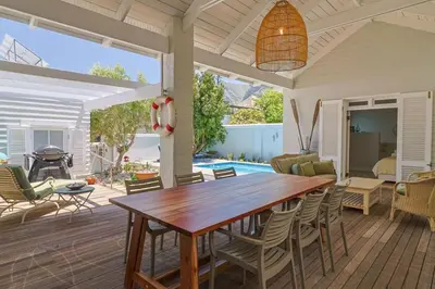 a dining room with a wooden table and chairs at Nautilus on Grotto Beach - heated pool in Hermanus