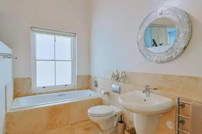a bathroom with a sink and a toilet and a mirror at Nautilus on Grotto Beach - heated pool in Hermanus