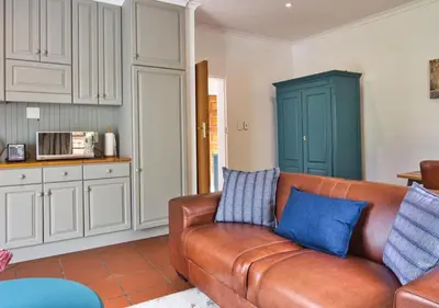 a living room with a brown couch and blue pillows at Wildeberg Elephants Trail Cottage in Franschhoek