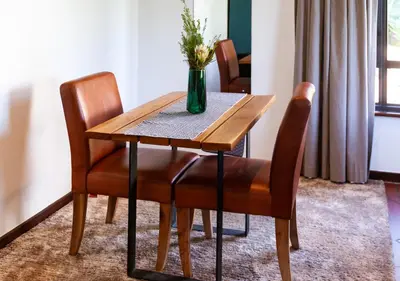 a wooden table with two chairs and a vase with flowers at Wildeberg Elephants Trail Cottage in Franschhoek