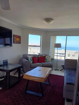 a living room with a couch and a table at Beach Club 150 Hermanus in Hermanus