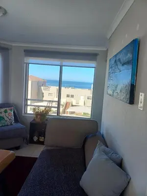 a living room with a couch and a large window at Beach Club 150 Hermanus in Hermanus