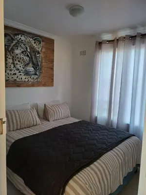 a bedroom with a bed with a tiger picture on the wall at Beach Club 150 Hermanus in Hermanus
