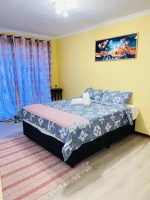 a bedroom with a bed in a room with blue curtains at GWMV Guest House in Cape Town
