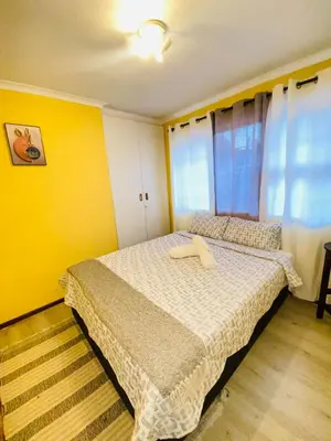 a bedroom with a bed with a yellow wall at GWMV Guest House in Cape Town