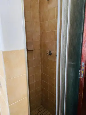 a bathroom with a shower with a tiled shower at GWMV Guest House in Cape Town