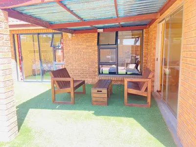 a patio with two wooden chairs and a table at GWMV Guest House in Cape Town