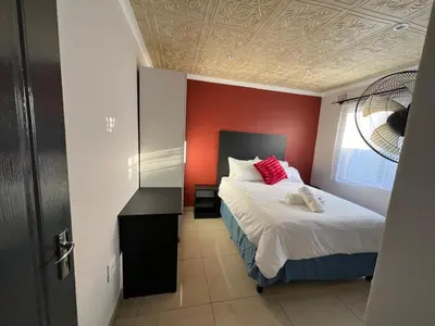 a bedroom with a bed with a red wall at Our Home Guest House in Bellville