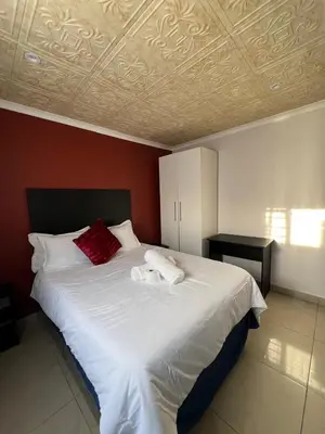 a bedroom with a large white bed with red pillows at Our Home Guest House in Bellville