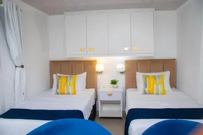 two beds in a small room with white cabinets at Optimum Stay Self Catering Accommodation - Twin Room 2 Single Beds in Parow
