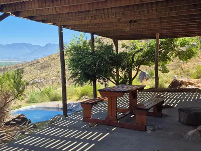 a wooden picnic table and bench under a roof at Avondrood Mountain House in Rawsonville