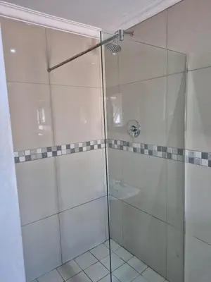 a bathroom with a glass shower with a sink at Maglovir Economy in Tiervlei