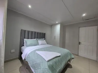 a bedroom with a large bed with a gray headboard at Maglovir Economy in Tiervlei
