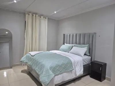 a bedroom with a large bed with a gray headboard at Maglovir Economy in Tiervlei