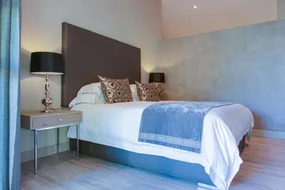 a bedroom with a large white bed and a nightstand at The Jordan Suites in Stellenbosch