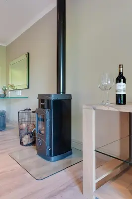 a wood fired stove in a room with a wine glass at The Jordan Suites in Stellenbosch