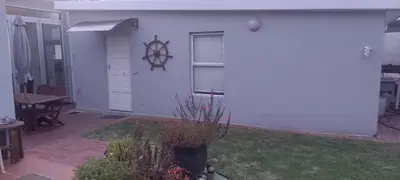 a white house with a yard with a table and a door at Amanda's Place in Hermanus
