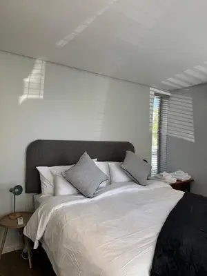 a bedroom with a large bed with white sheets and pillows at Black & White Self Catering in Paarl
