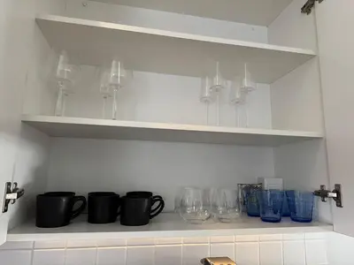 a kitchen shelf with cups and wine glasses on it at Black & White Self Catering in Paarl