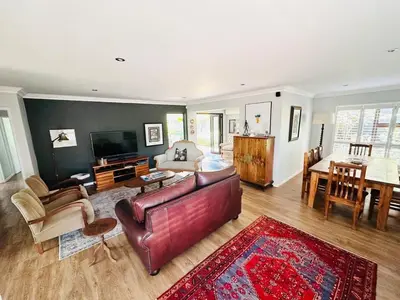 a living room with a leather couch and a table at Lelani Self Catering Cape Town in Oakdale