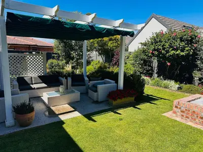 a patio with a couch and an umbrella in a yard at Lelani Self Catering Cape Town in Oakdale