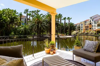 a patio with chairs and a view of a body of water at Canal Front Apartment Cape Town in Cape Town