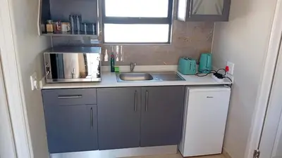 a small kitchen with a sink and a microwave at Bokwe's Guest House- Cape Town in Gordonʼs Bay