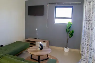 a living room with a green couch and a table at Bokwe's Guest House- Cape Town in Gordonʼs Bay