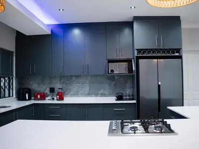 a kitchen with black cabinets and a black refrigerator at Bokwe's Guest House- Cape Town in Gordonʼs Bay