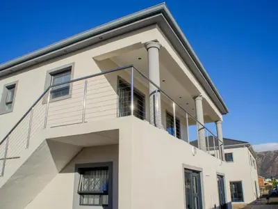 a white building with a balcony on top of it at Bokwe's Guest House- Cape Town in Gordonʼs Bay