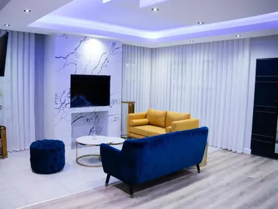 a living room with a blue couch and a tv at Bokwe's Guest House- Cape Town in Gordonʼs Bay