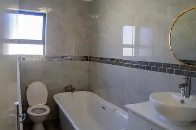 a bathroom with a tub and a sink and a toilet at Bokwe's Guest House- Cape Town in Gordonʼs Bay