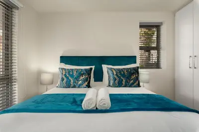 a bedroom with a blue and white bed with two towels at Mayfair 134 in Cape Town