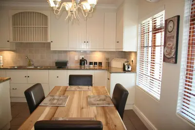 a kitchen with a wooden table and black chairs at Cape Robin Cottage in Franschhoek